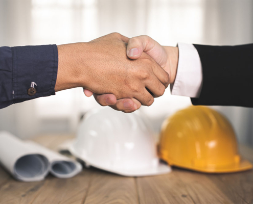 Stretta di mano con caschi da lavoro, simbolo di una partnership per la sicurezza aziendale