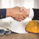 Stretta di mano con caschi da lavoro, simbolo di una partnership per la sicurezza aziendale
