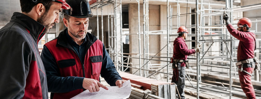 Audit di sicurezza in un cantiere edile con dispositivi di protezione individuale e professionisti al lavoro.