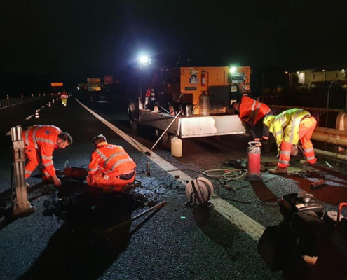 Lavoratori in un cantiere stradale notturno con DPI ad alta visibilità e illuminazione di sicurezza
