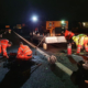 Lavoratori in un cantiere stradale notturno con DPI ad alta visibilità e illuminazione di sicurezza