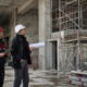 Operai su cantiere indossano DPI durante ispezione di sicurezza.