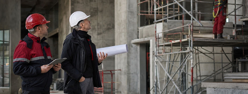 Operai su cantiere indossano DPI durante ispezione di sicurezza.